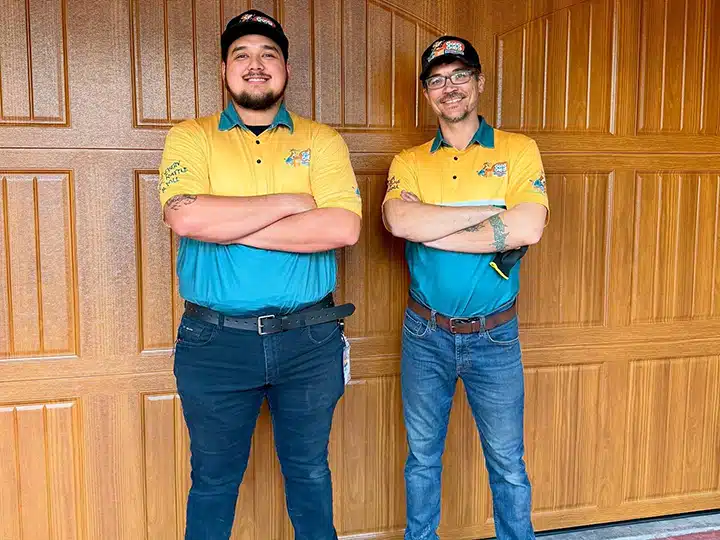Good Golly Garage Doors technicians smiling in front of new residential garage door.